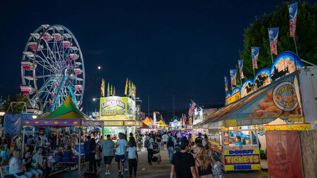 A carnival at night with a ferris wheel in the background